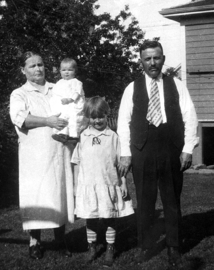 Anna Schmidt holding her granddaughter, Donna Hawes, the daughter of Mary (nee Schmidt) Hawes. Esther Smith stands with her father Johannes Schmidt. The photograph was taken in Portland about 1927.